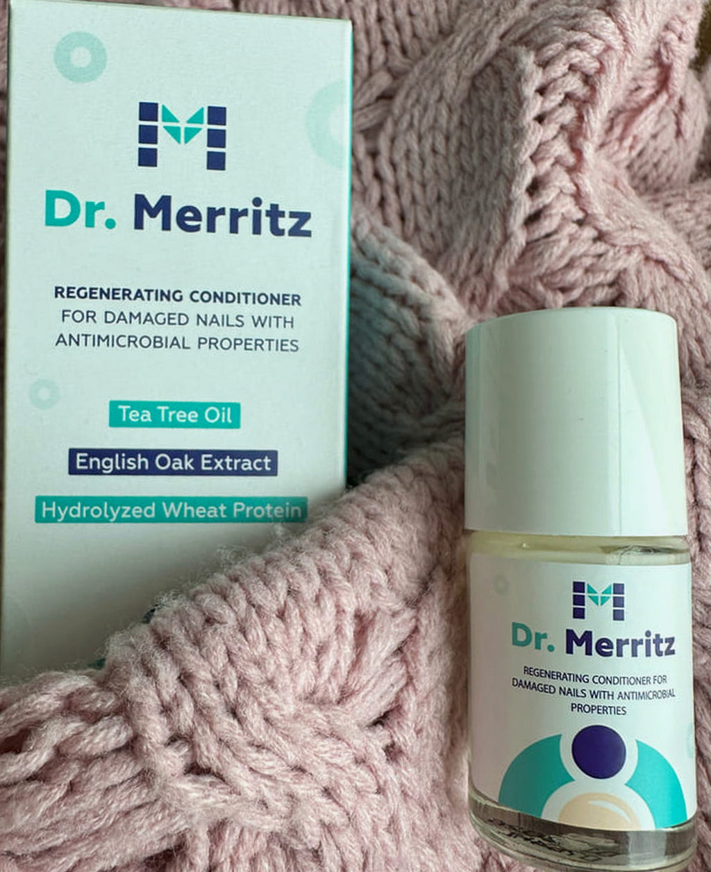 Opakowanie i lakier Dr. Merritz na różowym dzianinowym swetrze